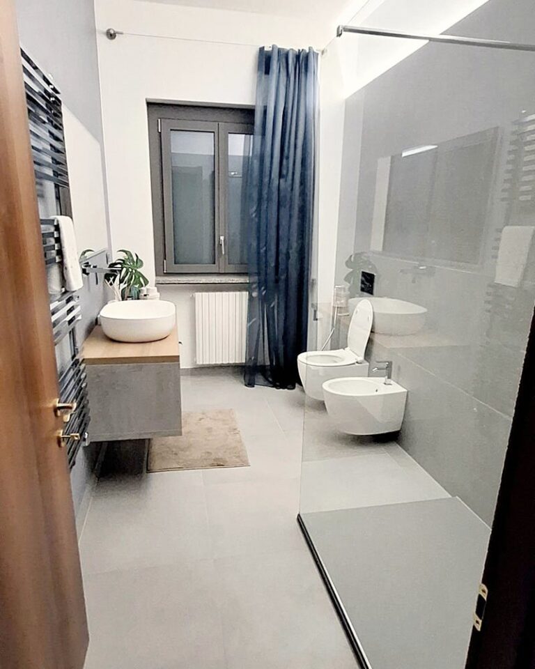 Lo stesso bagno dopo i lavori: doccia in vetro al posto della vasca e sanitari sospesi