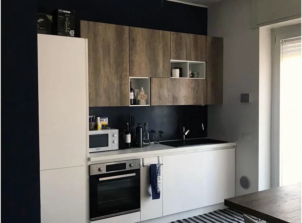Cucina ristrutturata con basi bianche, pensili in legno e piano scuro