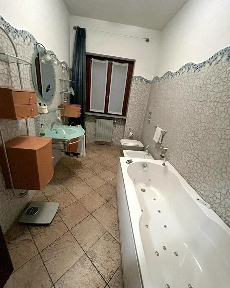 Bagno prima dei lavori, con vasca idromassaggio e rivestimento a mosaico