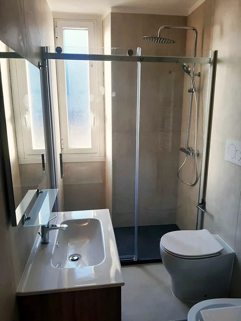 Lo stesso bagno con doccia in nicchia e mobile lavabo scuro