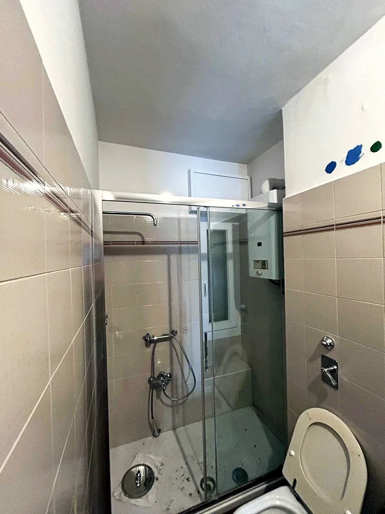 Bagno prima dei lavori, con doccia piastrellata e mosaico blu