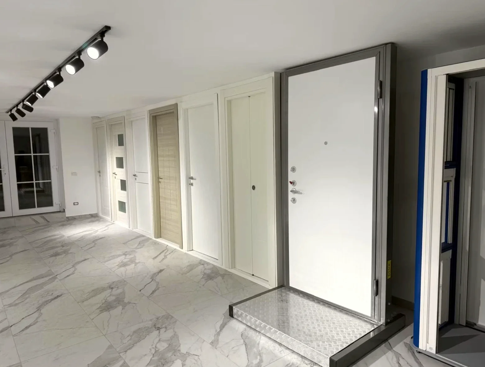 Porta blindata bianca con cornice grigia, spioncino e serrature, in esposizione